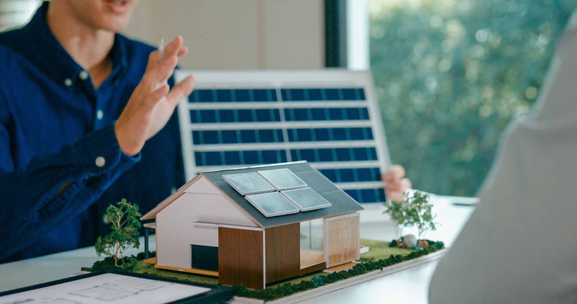 Closeup of young Asian couple in detailed consultation with real estate agent, who is highlighting advantages of home with solar panels. Consulting on Eco-Friendly Home with Real Estate Agent.